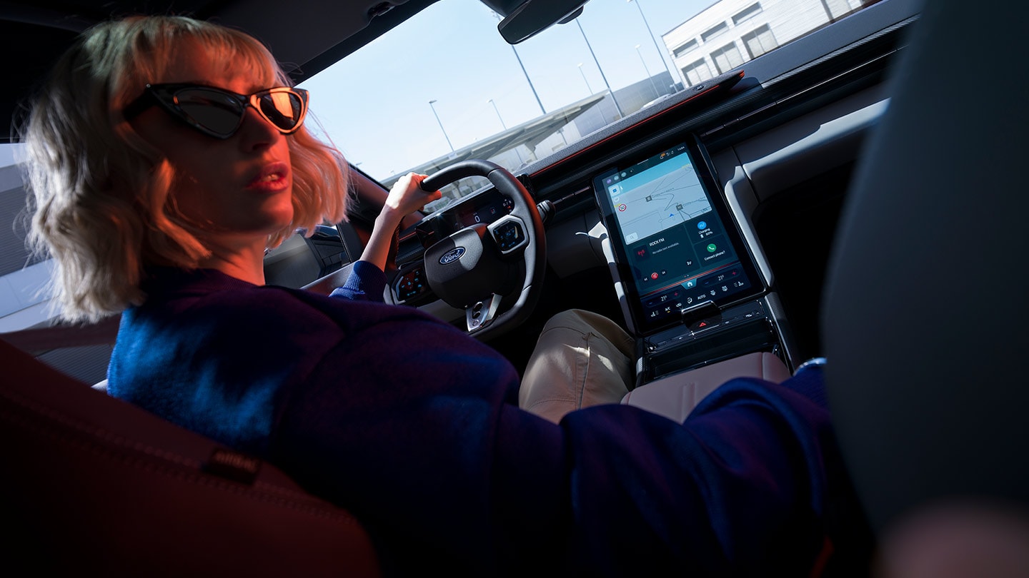 Femeie la volanul noul Ford Capri® cu vedere spre volan, bord și ecranul tactil mare SYNC® Move.