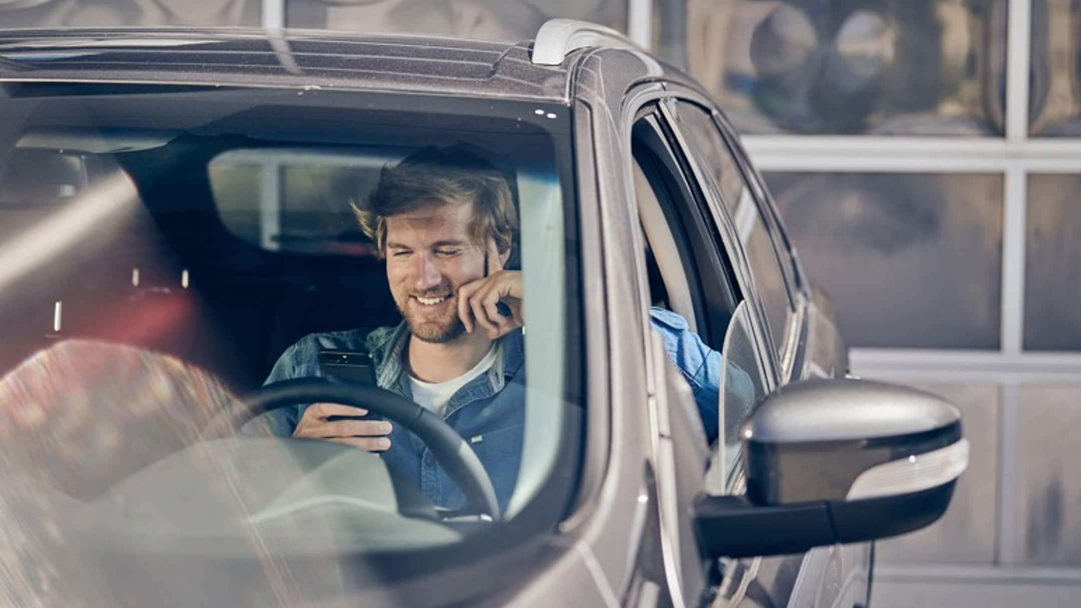 Person sitting in car and checking mobile phone